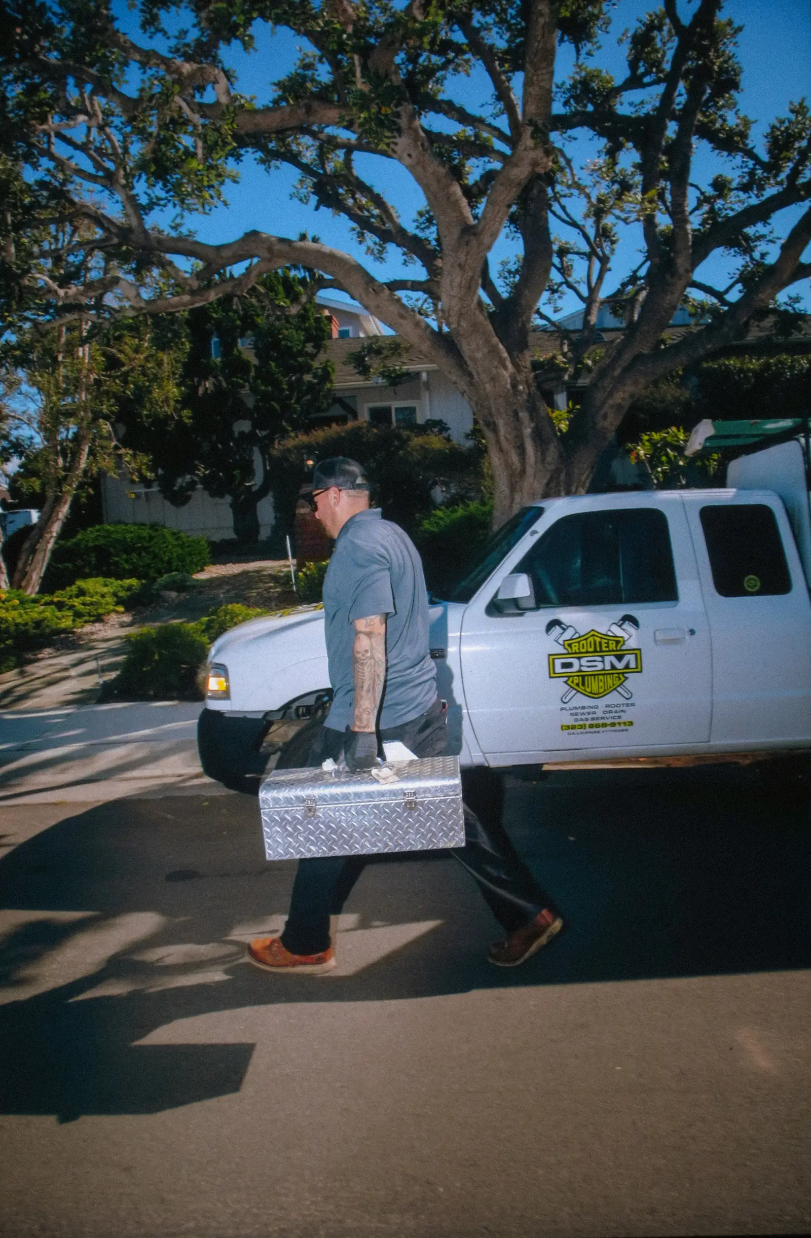 DSM Rooter Plumbing technician with branded truck and toolbox